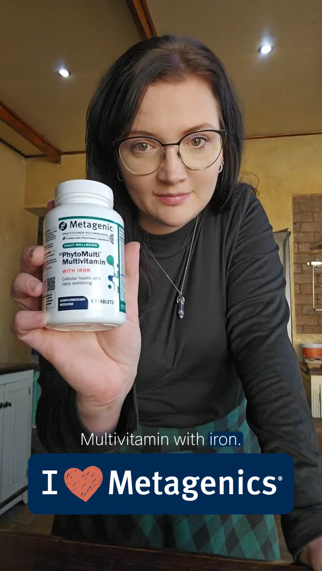 A woman holding a bottle of Metagenics PhytoMulti Multivitamin with Iron.