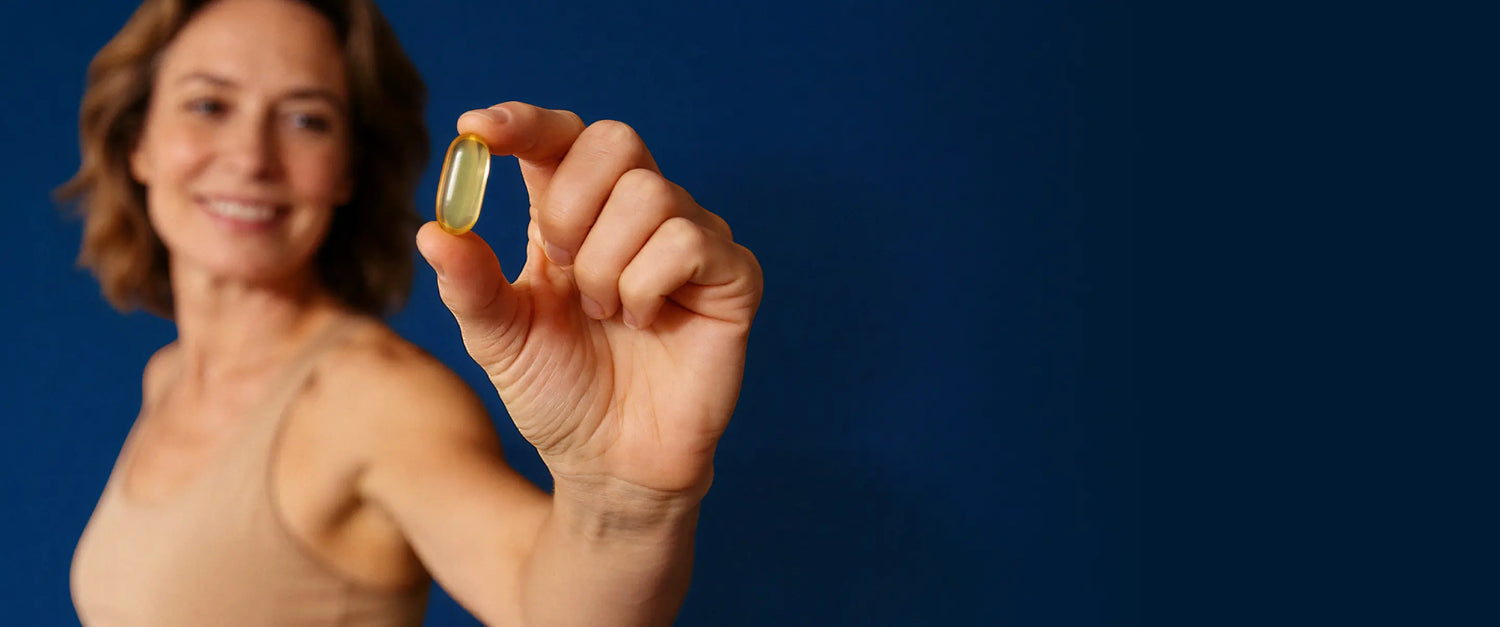 Woman holding a supplement capsule against a blue background